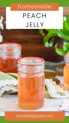 two jars filled with peach jelly sitting on top of a table next to some flowers