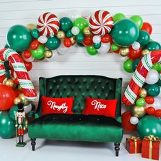 a green couch sitting under a christmas balloon arch