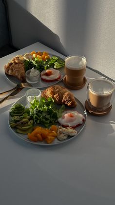 two plates with food on them sitting on a table next to cups and saucers