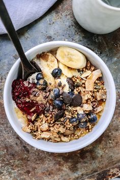 a bowl filled with granola, bananas and blueberries