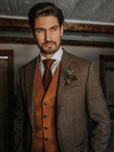 a man wearing a suit and tie with a flower in his lapel, looking at the camera