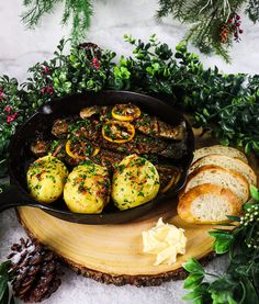 an iron skillet filled with potatoes and meats on top of a wooden cutting board