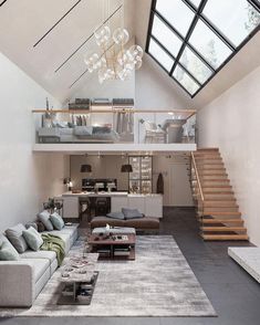 a living room filled with lots of furniture and a staircase leading up to the top floor