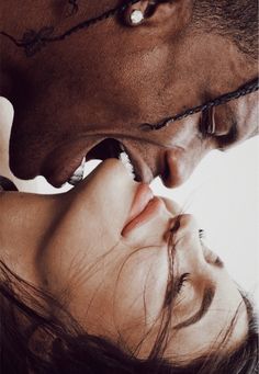 a man kissing a woman's forehead with barbed wire around her neck and nose