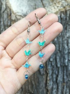 a person is holding some kind of earrings in their hand, with blue beads hanging from them