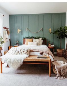 a bed room with a neatly made bed next to a table and two plants on the wall