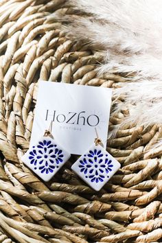 a pair of blue and white earrings sitting on top of a woven basket