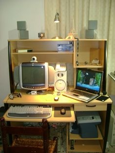 a computer desk with two monitors and a laptop on it, in front of a bookshelf