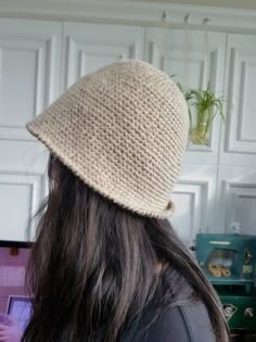 a woman with long hair wearing a knitted hat looking at her laptop computer screen