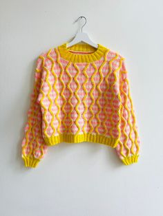 a yellow and pink sweater hanging on a white wall