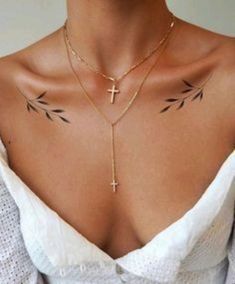 a woman with tattoos on her chest wearing a cross and chain choker necklace in gold