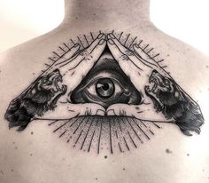 a man's back with two hands holding an all seeing eye tattoo on his chest