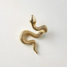 a gold snake brooch sitting on top of a white surface