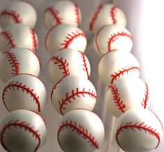 many white and red baseballs on sticks in a display case, with one ball at the top