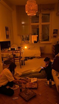 two people sitting on the floor in a living room at night looking at their cell phones