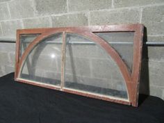 an old wooden window sitting on top of a black cloth covered table next to a brick wall