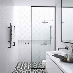 a bathroom with black and white tiles on the floor, shower, and sink area