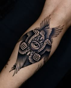 a black and white owl with an eye tattoo on it's arm is shown