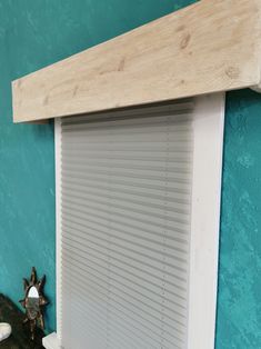 a room with blue walls and white blinds on the window sill, along with a wooden headboard