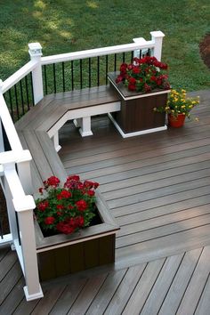 a wooden deck with potted plants and flowers on the railings, along with two benches