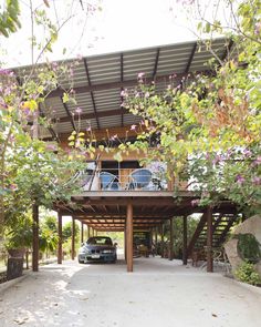 a car is parked in front of a house with trees and flowers on the roof