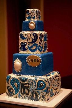 a three tiered cake with blue and white designs on it's sides, sitting on top of a table