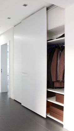 an open closet with clothes on hangers and other items in the room behind it