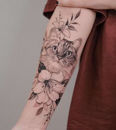 a woman's arm with a cat and flowers tattoo on the left side of her arm