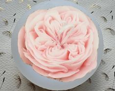 a pink frosted flower in a blue bowl on a doily with dandelions