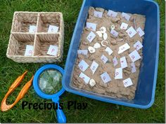 sand and scissors are laying on the grass next to a tray with numbers in it