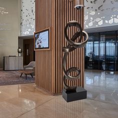 a sculpture in the middle of a lobby with a tv on it's stand