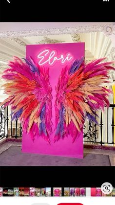 an image of a pink sign with purple and red feathers on it's side