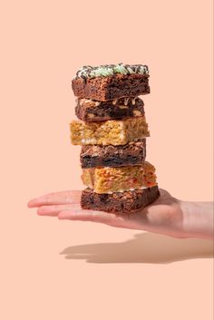 An extended hand holds a stack of 6 brownie slices in front of a solid light pink background Biscuit Product Photography, Bakery Photography Ideas, Cake Product Photography, Desert Food Photography, Brownies Photography, Colorful Food Photography, Brownie Photography, Gourmet Brownies, Modeling Studio