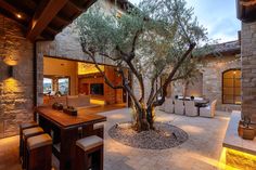 an outdoor dining area with table, chairs and a tree in the middle of it