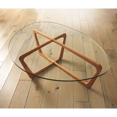 a glass coffee table with wooden legs and an unusual design on the top, sitting on a hardwood floor