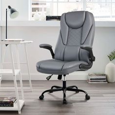 a gray office chair sitting on top of a hard wood floor next to a window