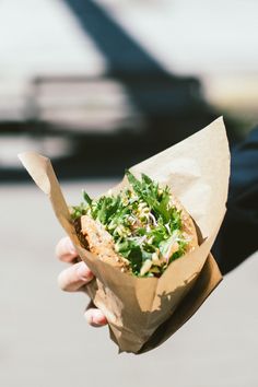 a person holding a paper bag filled with food and veggies on top of it