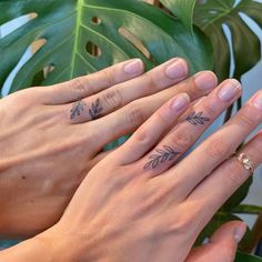 two people holding hands with tattoos on their fingers and one has a ring in the other hand