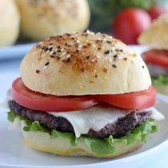 a hamburger with tomatoes, lettuce and cheese is on a plate next to other burgers