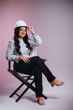 a woman sitting on top of a chair wearing a white hat and holding her hand up to her face