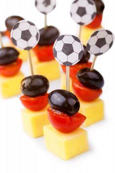 several pieces of cheese topped with black and white soccer balls on top of tomato slices