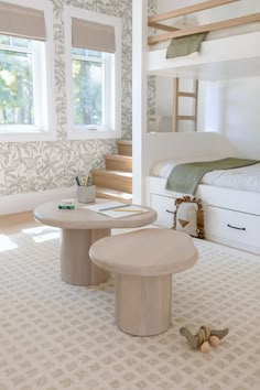 a bedroom with bunk beds and two tables on the floor next to each other in front of a window