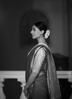 a woman standing in front of a mirror wearing a sari and looking off to the side