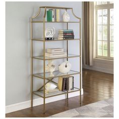 a gold shelf with books and other items on it next to a window in a room