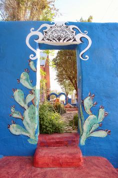 a blue wall with a painted doorway and steps leading up to the entry way that leads into a garden