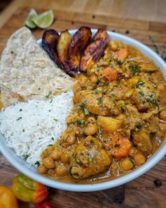 a white plate topped with rice and curry next to some fried food on top of a wooden cutting board