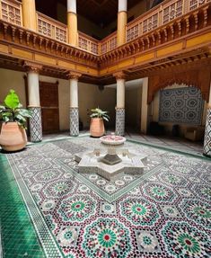 an elaborately decorated courtyard with potted plants in the center and decorative tiles on the floor