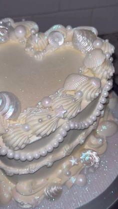 a heart shaped cake with shells and pearls on it's sides, sitting on a table