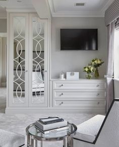 a bedroom with white furniture and a flat screen tv