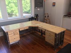 an office desk made out of wood and metal with two drawers on each side, in front of a large window